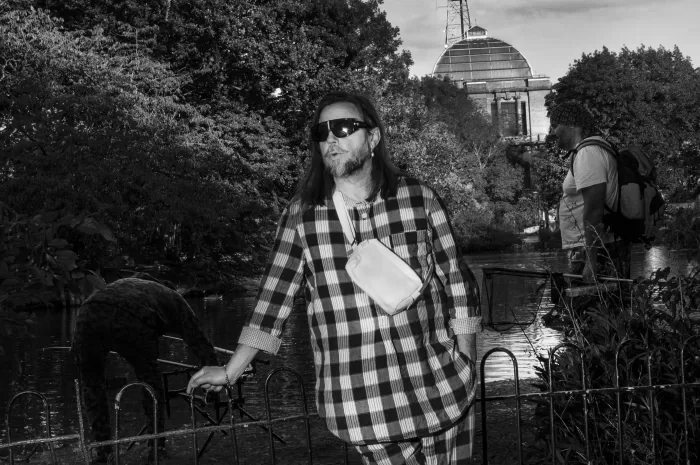 A black and white photograph of Mark Leckey stood outside