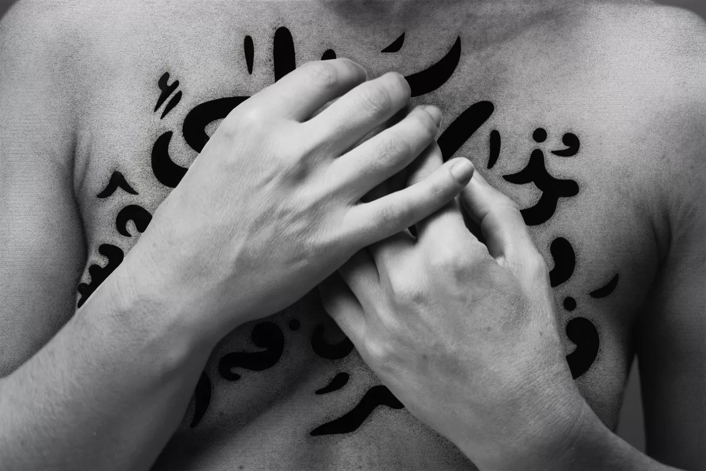 A black and white photograph of a pair of hands from 'The Fury' series by Shirin Neshat