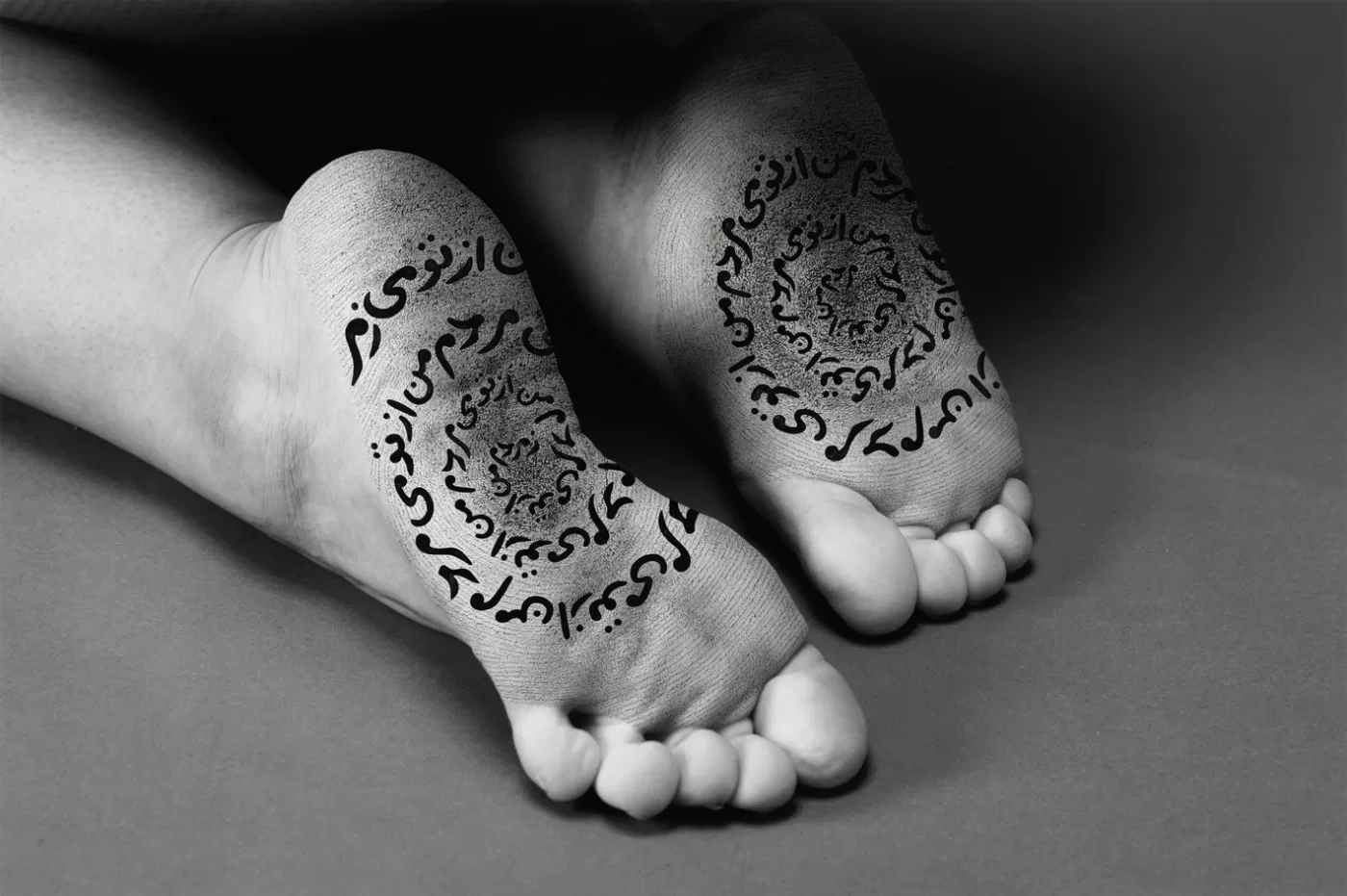 A black and white photograph depicting the underside of someone's feet from 'The Fury' series by Shirin Neshat