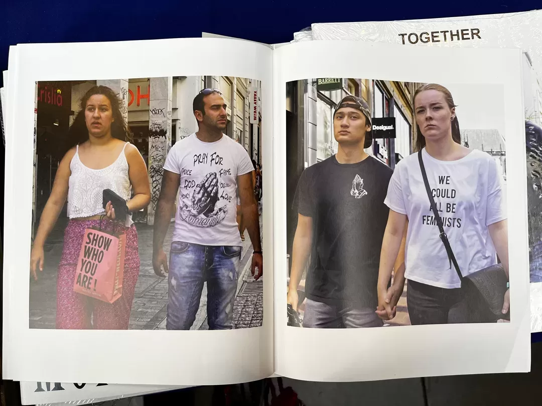 A photograph of a double-page spread from a photobook featuring candid photographs of couples walking in the street wearing slogan t-shirts