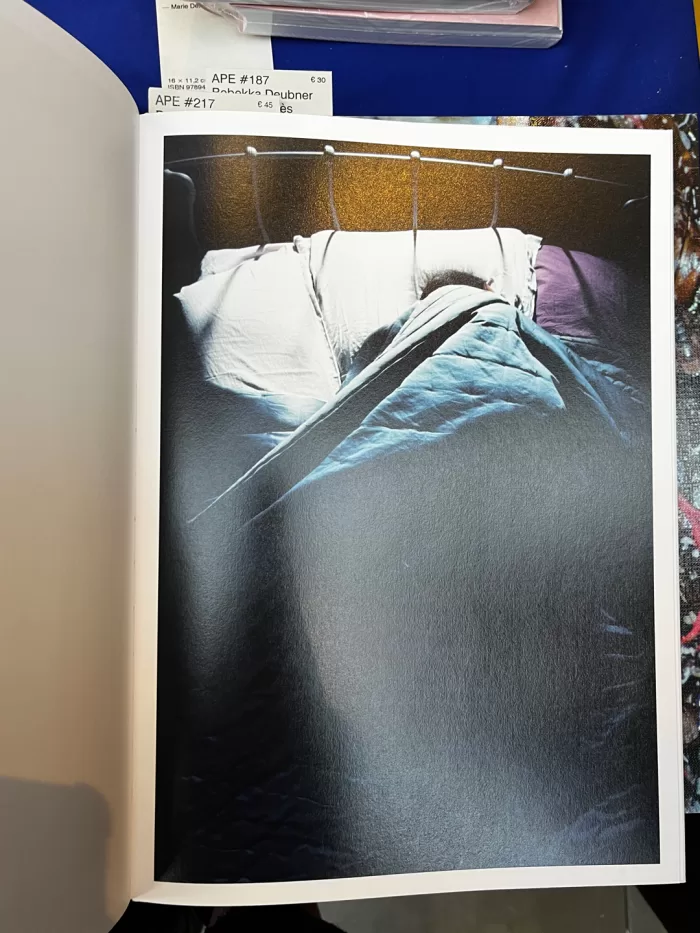 A photograph of a page from Dorothy Sing Zhang's book 'Like Someone Alive' picturing a person sleeping in bed