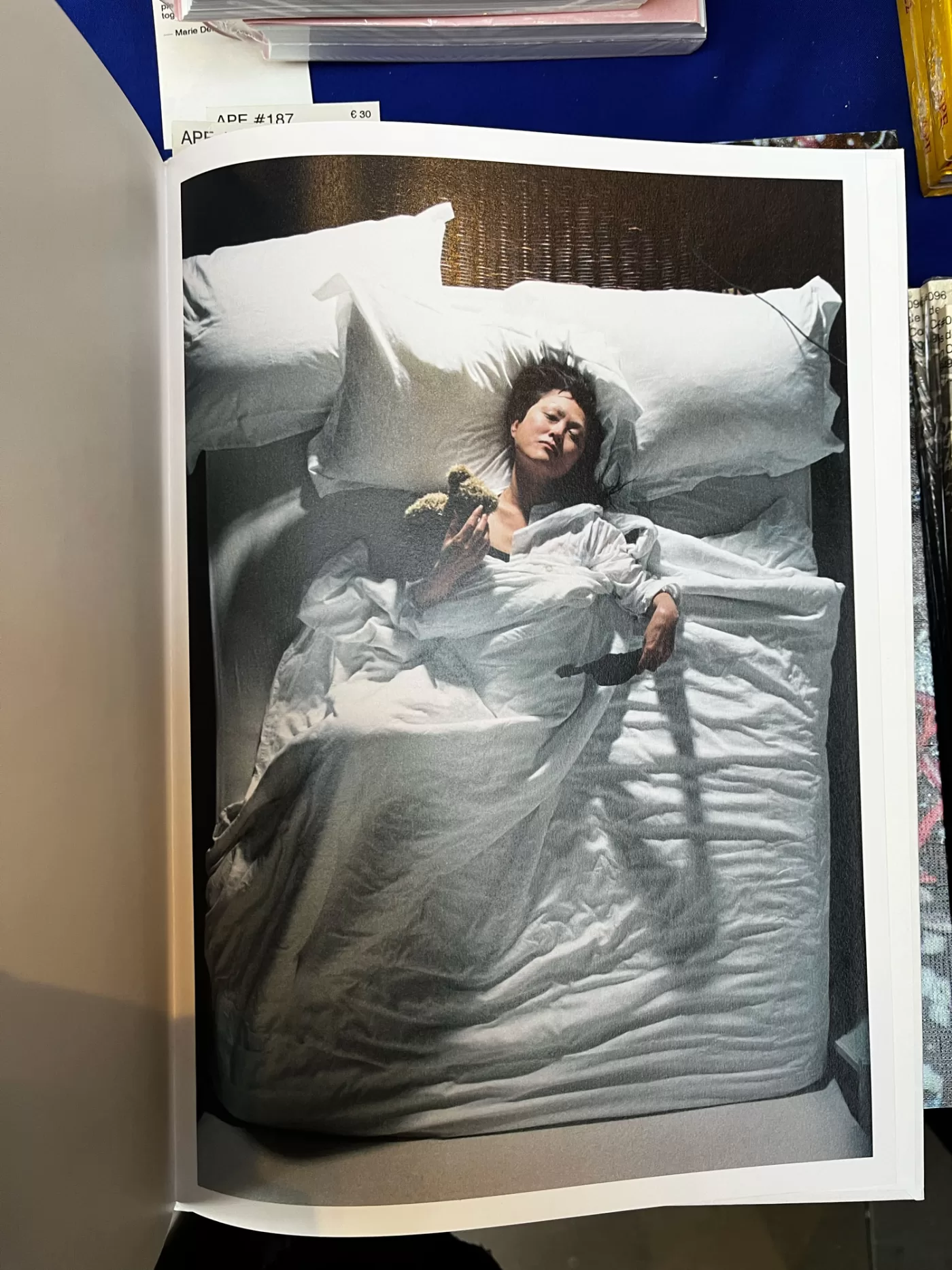 A photograph of a page from Dorothy Sing Zhang's book 'Like Someone Alive' picturing a person resting in bed