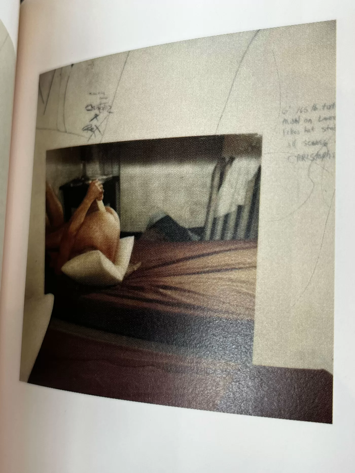 A photograph of a page from a photography book featuring a photo of a couple in bed, surrounded by some writing and sketches