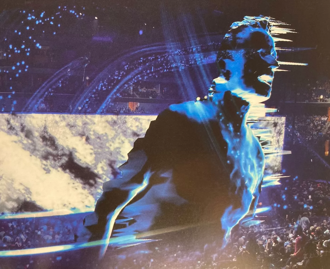 An image of a large hologram of a man projected over the crowd of a concert