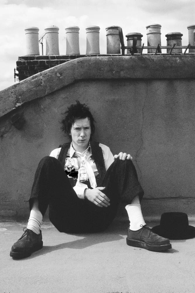 Black and white photograph of a man sat on a rooftop