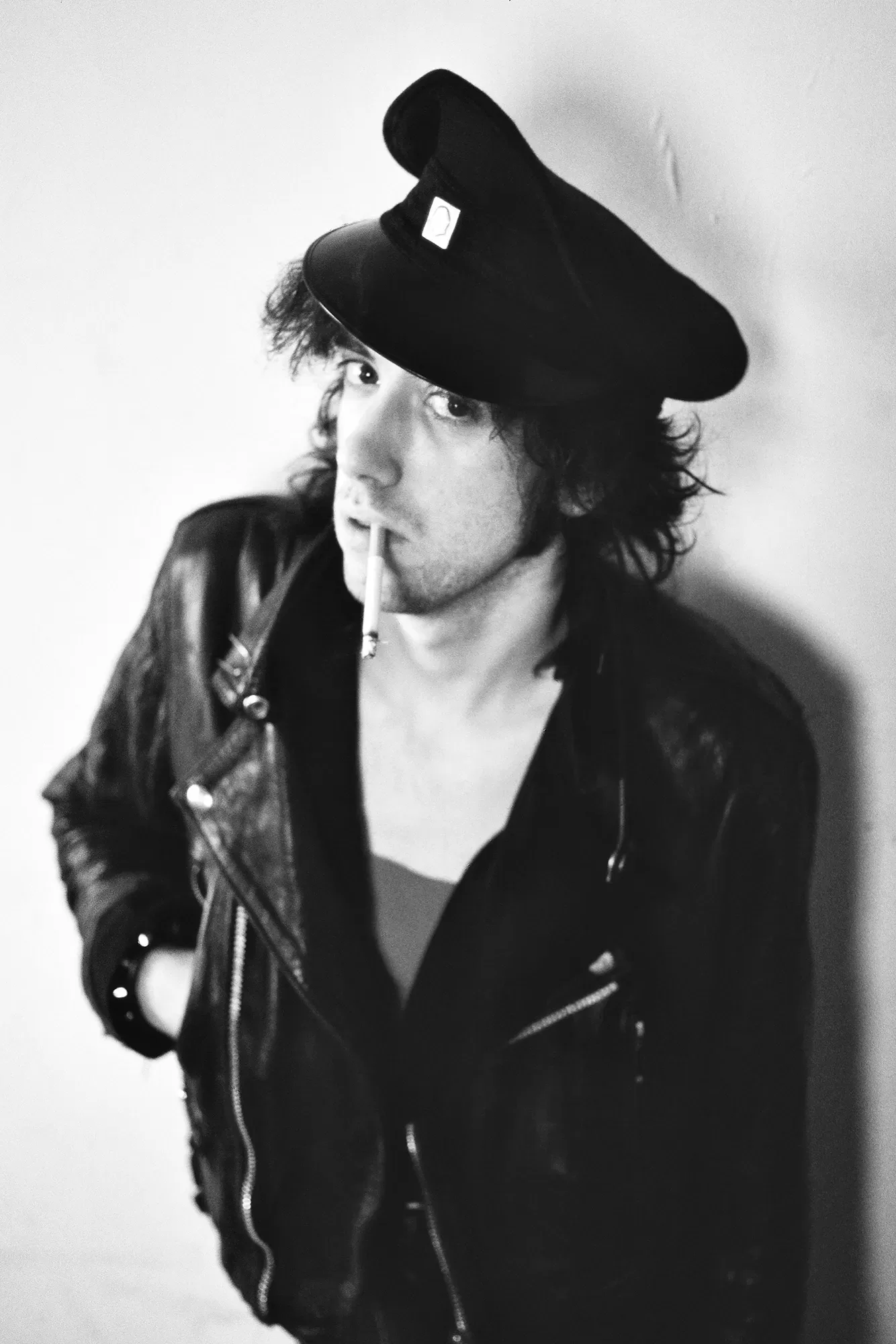 Black and white photograph of Mick Jones wearing a hat smoking a cigarette