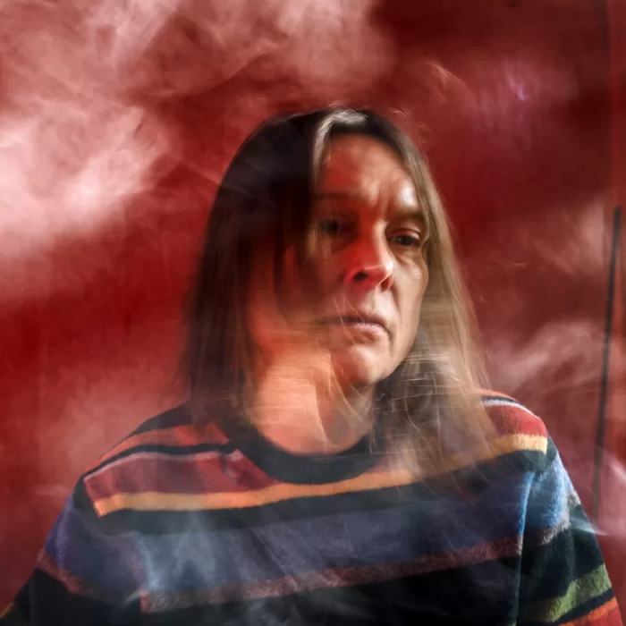 A photograph of Sarah Lucas smoking a cigarette in 'Red Sky Cah'