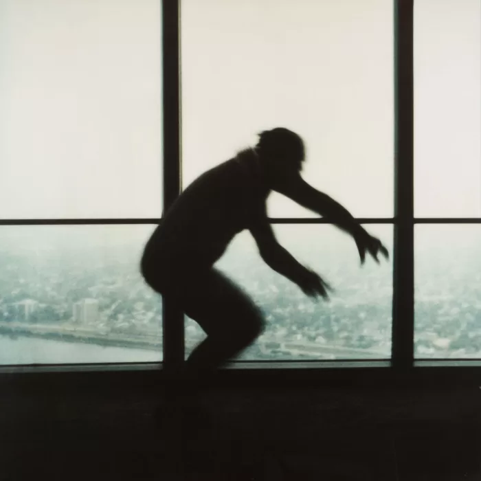 A high contrast photograph of a man jumping in the air with a city skyline in the background