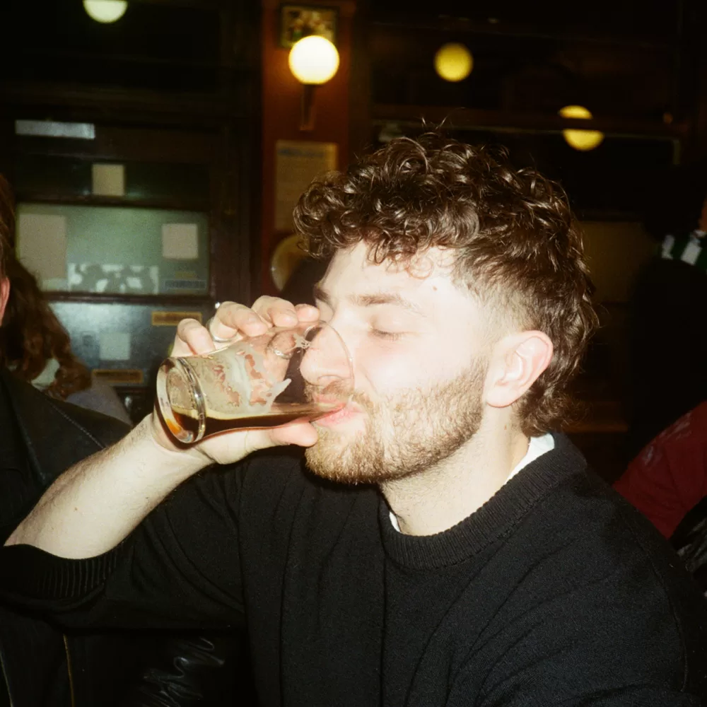 A photograph of Leon Scott-Engel drinking a half pint of Guinness.