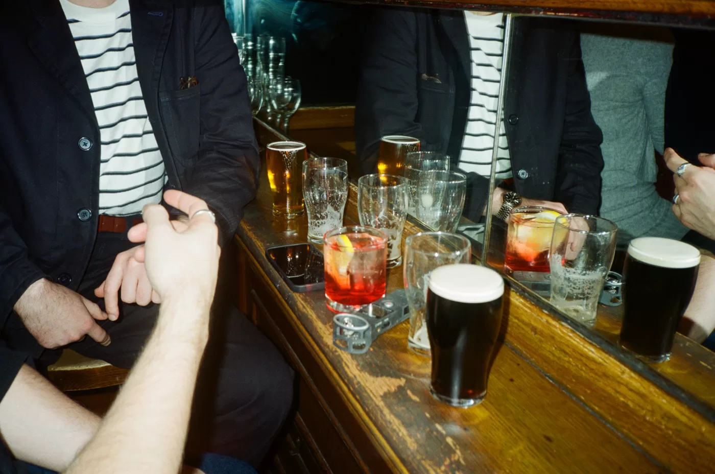 A photograph of a bar covered in drinks. Behind the bar is a mirror.