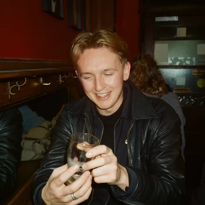 A photograph of George Richardson looking at a half pint of Guinness.