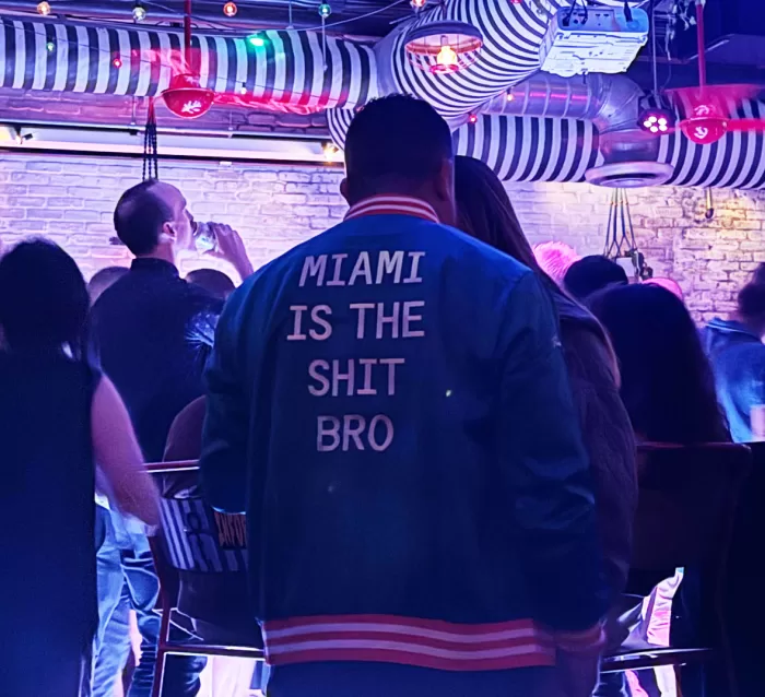 A photograph of a man's jacket that reads 'Miami is the shit bro' taken at a party during Miami Art Basel