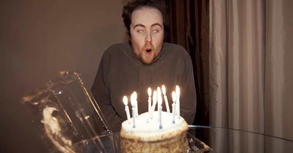 Film still from Irish filmmaker Kevin Brennan's 'Checked Out', picturing a man blowing out birthday candles