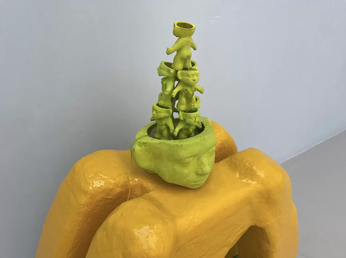 Claudia Martignetti's sculpture of a fountain made of miniature green troll sculptures